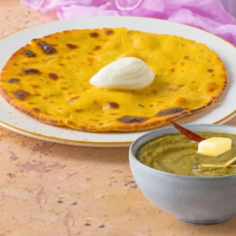 A classic Punjabi combo of golden cornmeal flatbread and creamy mustard greens, cooked with spices and served with fresh butter and jaggery.