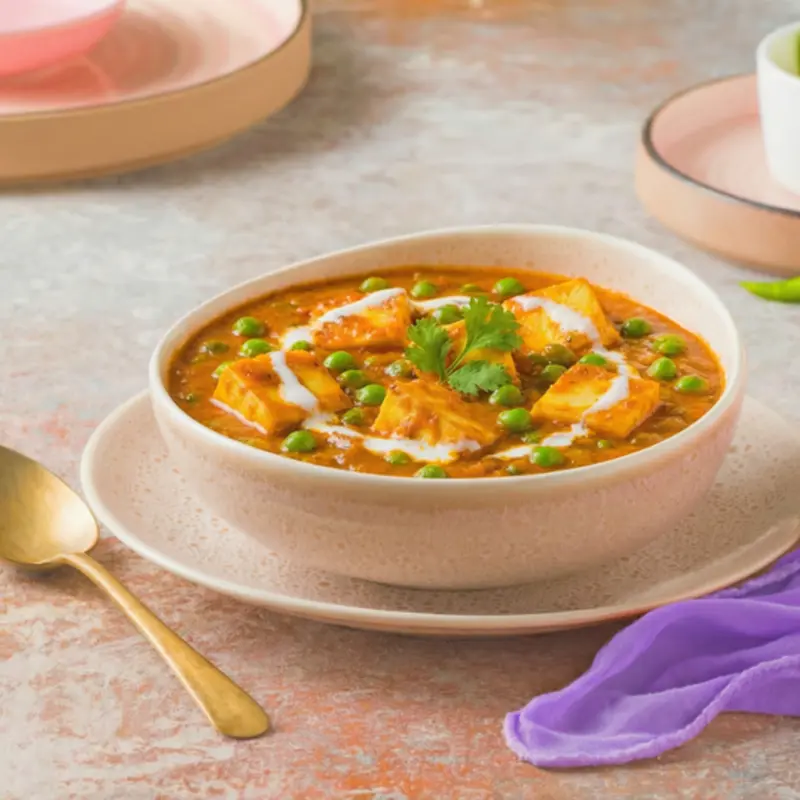 Soft paneer cubes and sweet green peas simmered in a lightly spiced tomato-onion gravy, finished with a touch of cream—comforting, balanced, and timeless.