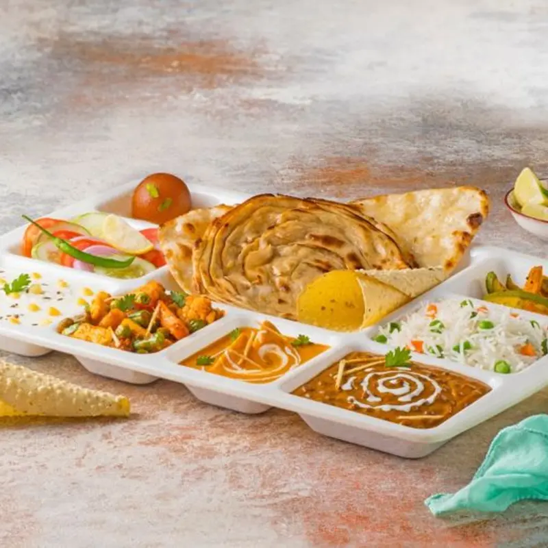 Thali served in combination of one naan, one prantha, dal makhni, paneer subzi, seasonal vegetable, boiled rice, raita, salad, papad and sweet