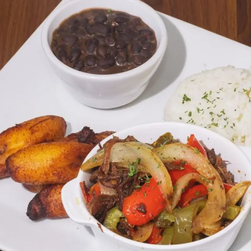 Tender, slow-cooked shredded beef simmered in a savory tomato-based sauce with bell peppers, onions, and garlic, served with 2 sides. A classic Cuban comfort dish full of rich, bold flavors. at The Food Corner | Toast