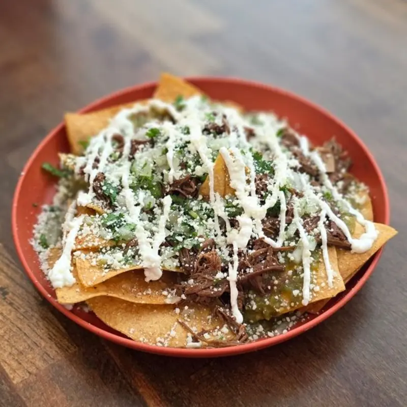 Crispy tortilla chips bathed in rich birria consommé and salsa, topped with tender birria beef, crumbled cotija cheese, onion, and fresh cilantro.